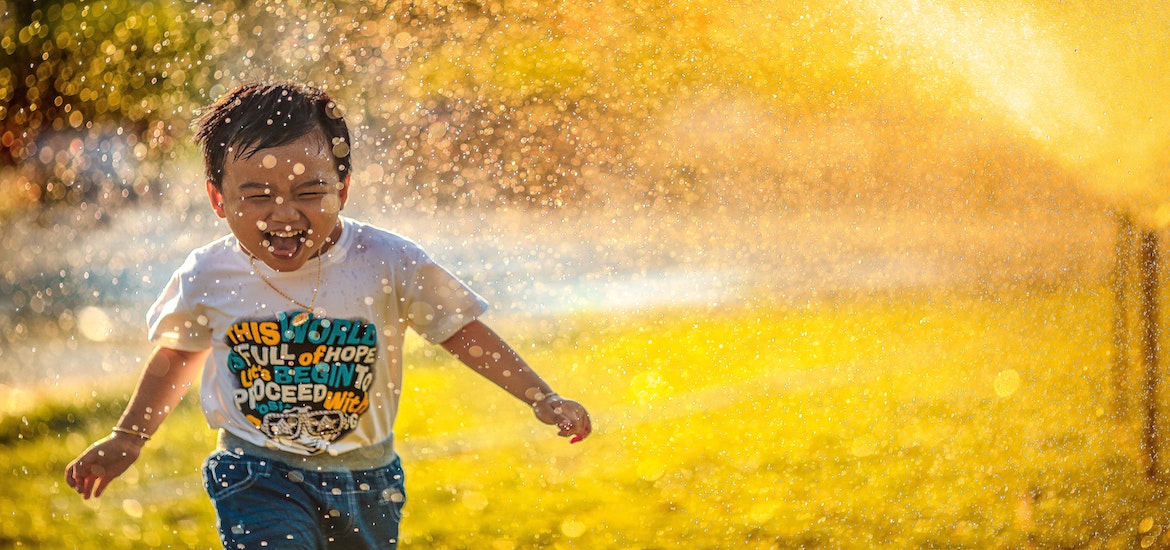 happy child runs through sprinkler