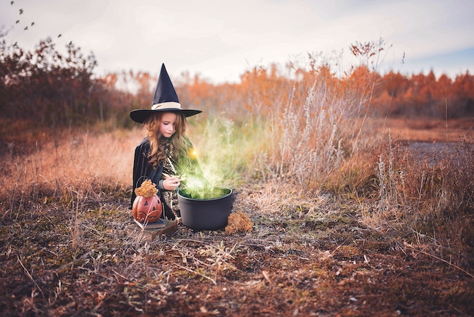 girl in witch costume with cauldron